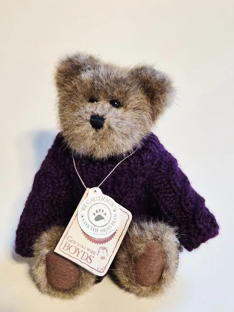Frosted brown Boyds teddy bear sitting upright in a plum cable-knit turtleneck sweater with original paper hang tags on a string around his neck