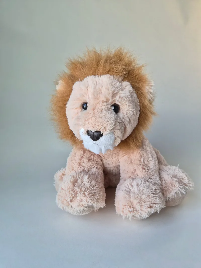 A tan Aurora lion plush sitting upright with a fluffed golden mane and white chin patch