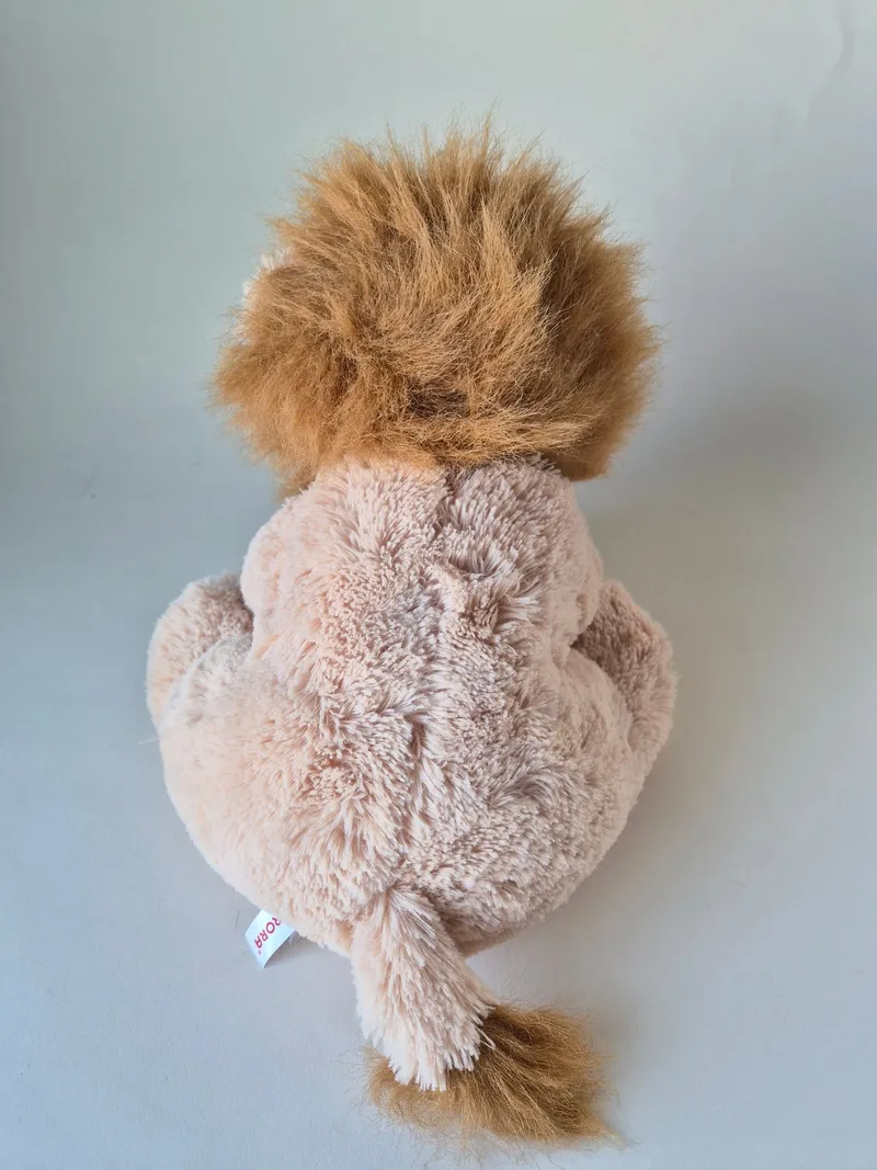 Back view of the lion plush showing the full mane, tail tuft, and Aurora fabric tag