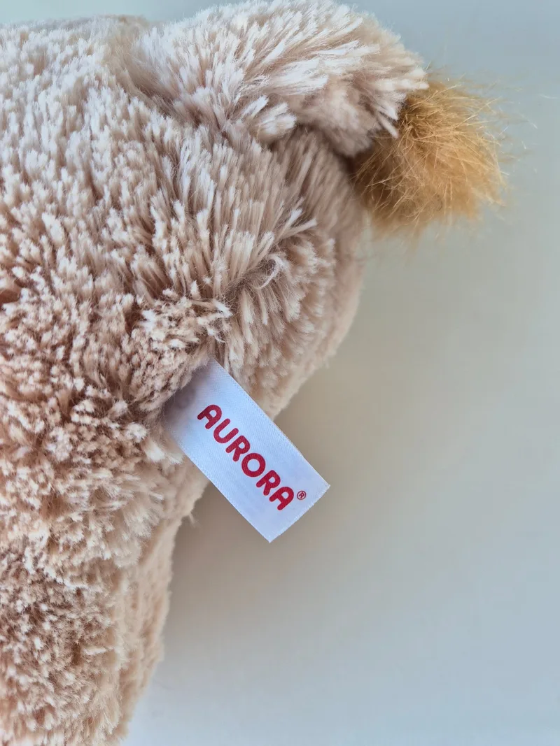Close-up of the Aurora brand tag stitched into the lion plush's back seam
