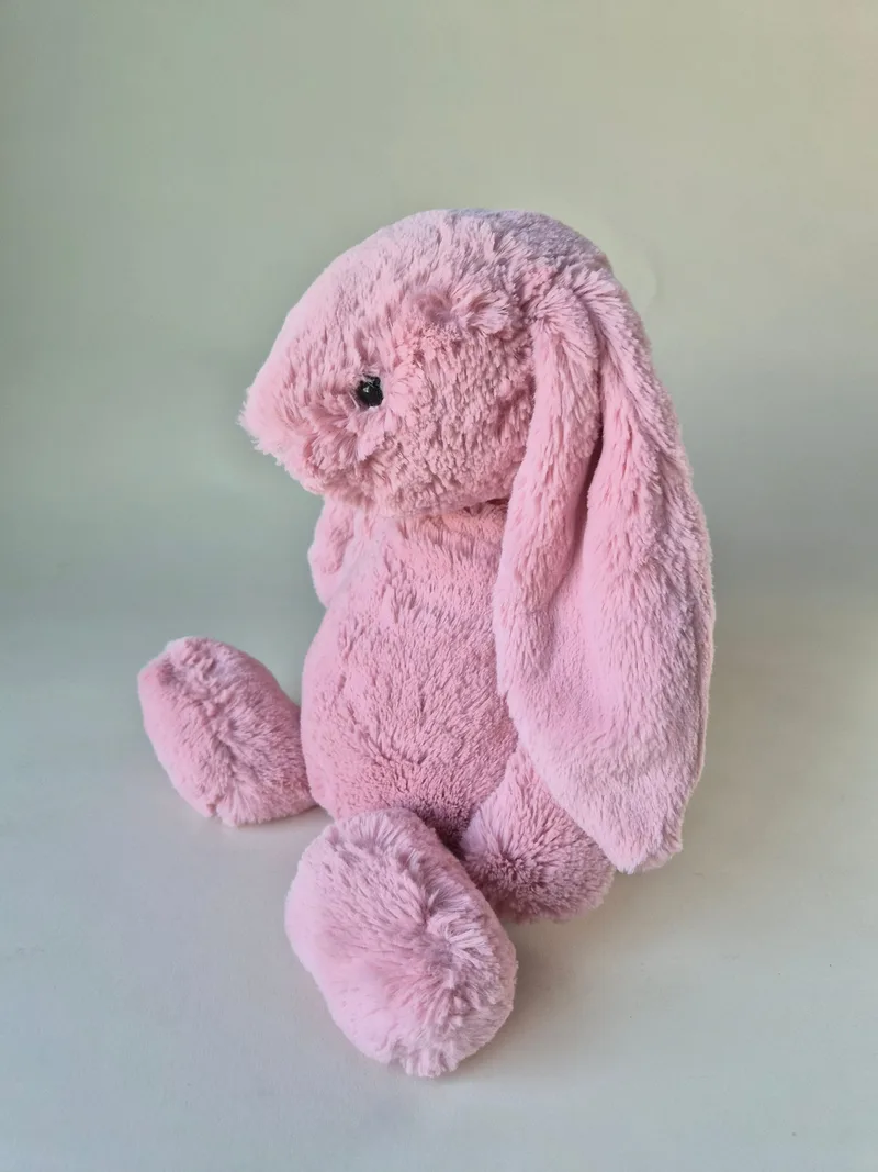 Side view of the pink bunny seated, showing one long ear draped down