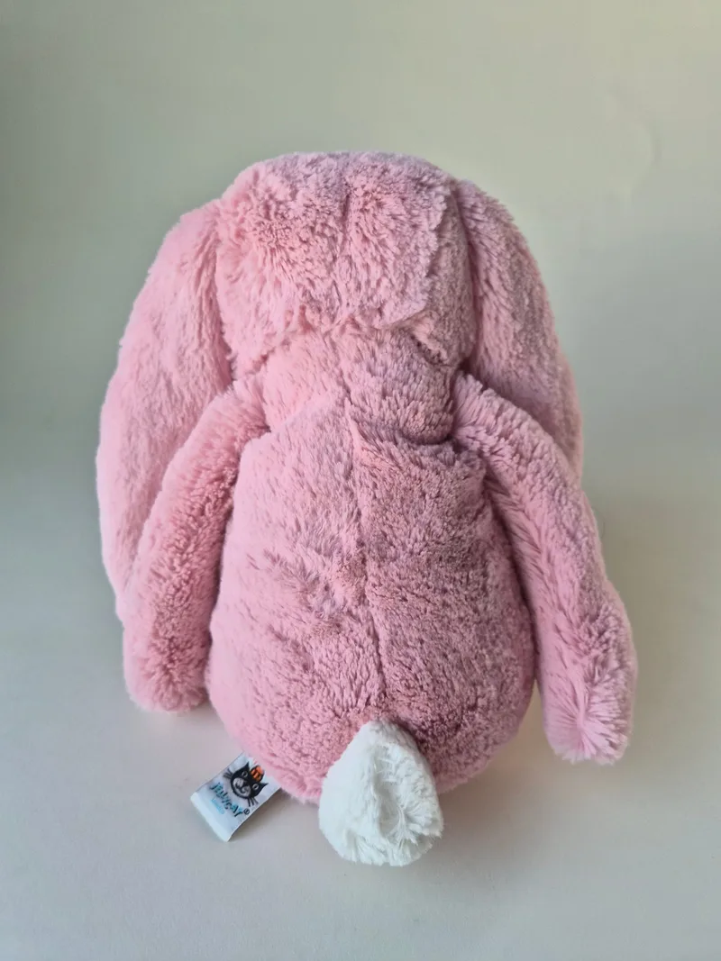 Back view of the bunny showing cream bobtail and a small brand tag at the seam