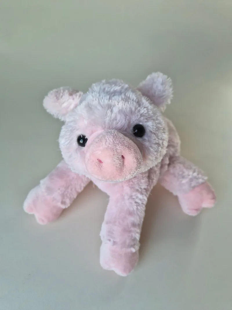 Pink Aurora plush pig with grey-white frosted fur lying front-on, both black bead eyes and rose snout visible