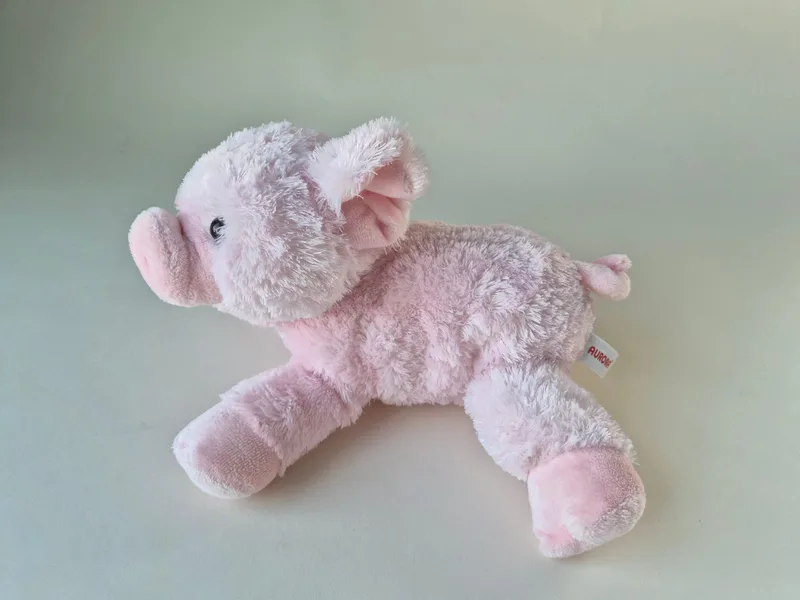 Side view of the pink piglet showing frosted back fur and a white side tag
