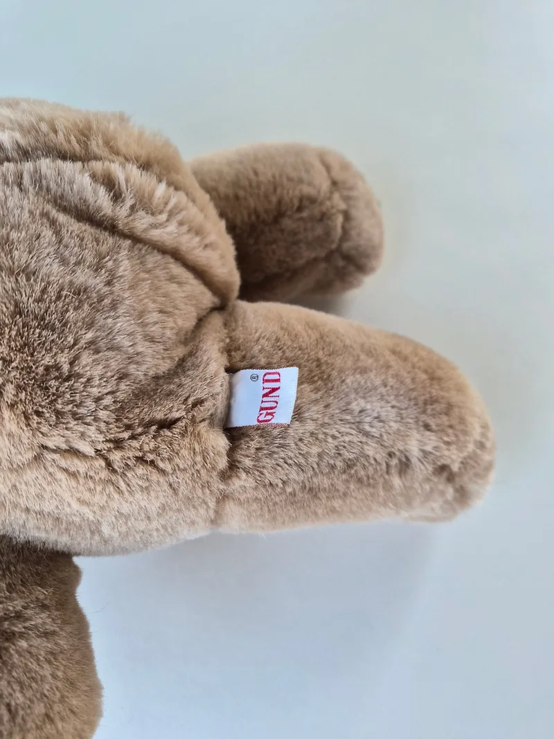 Close-up of the bear's snout and ear with the red woven GUND side-seam tag visible