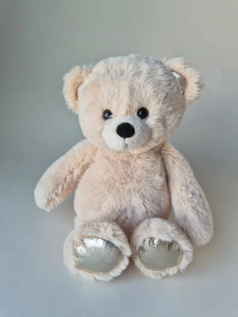 Full view of a seated cream teddy bear showing metallic silver foot pads and ear tips