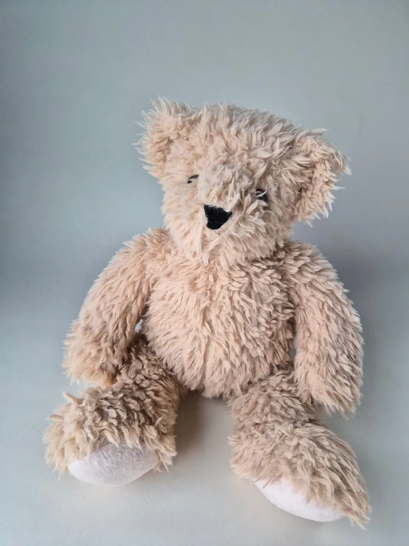 Shaggy pale-honey Vermont Teddy Bear seated, with tousled fur, ivory muzzle and paw pad, and stitched black nose