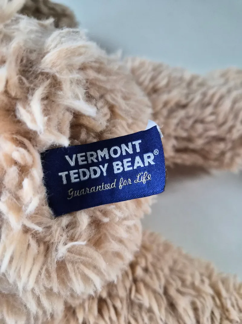 Close-up of navy side-seam tab reading Vermont Teddy Bear, Guaranteed for Life