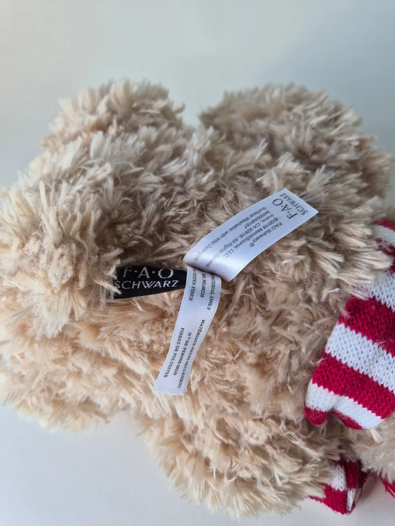 Detail of the FAO Schwarz sewn tags and satin care label between the bear's legs