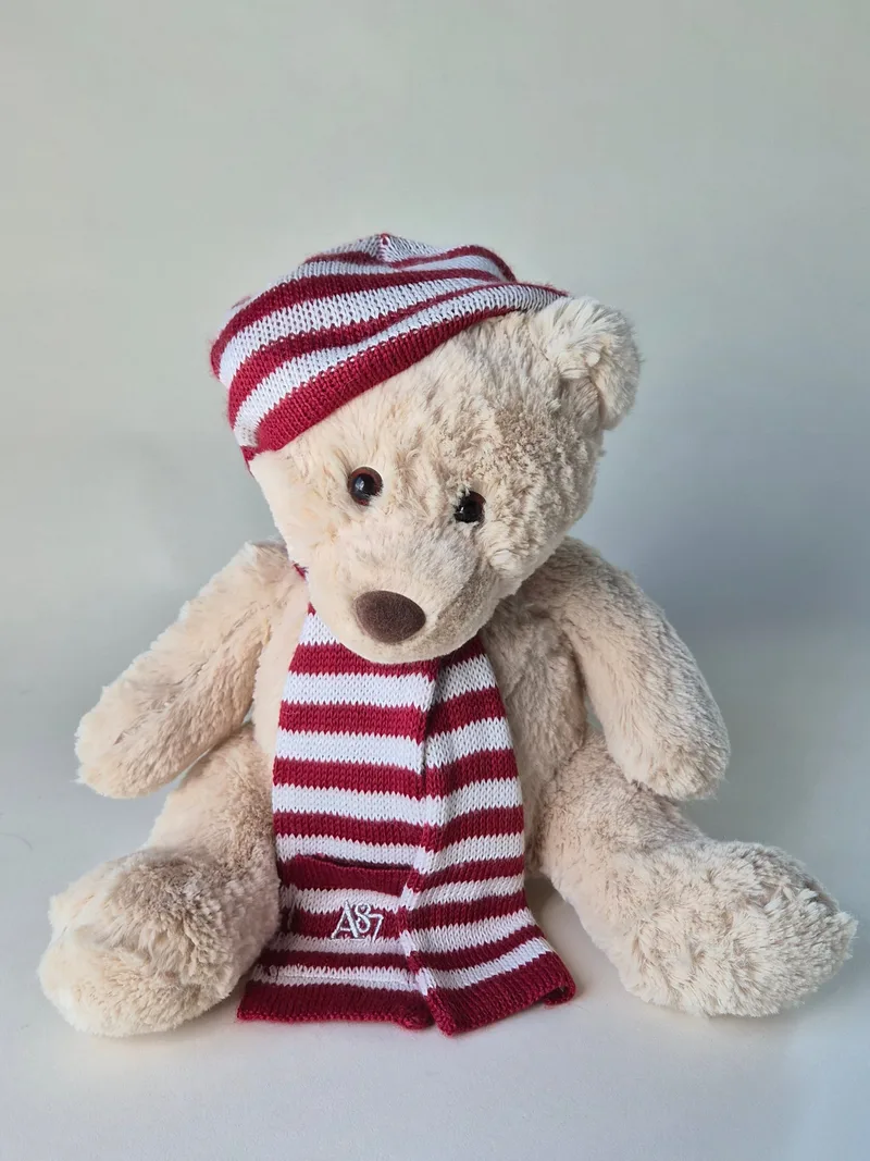 Ivory shag teddy bear with amber eyes wearing a red-and-white striped A87 knit scarf, seated