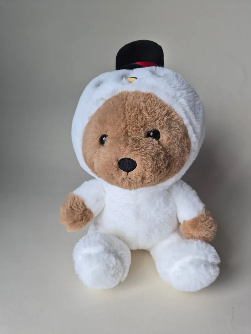 Small brown Russ teddy bear seated in a white plush snowman costume with a hooded head and black top hat, face peeking out the front