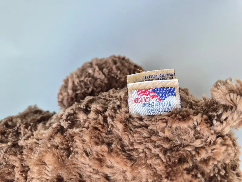 Close-up of the bear's Gund 'America's Teddy Bear' flag seam tag reading polyester fibers and plastic pellets