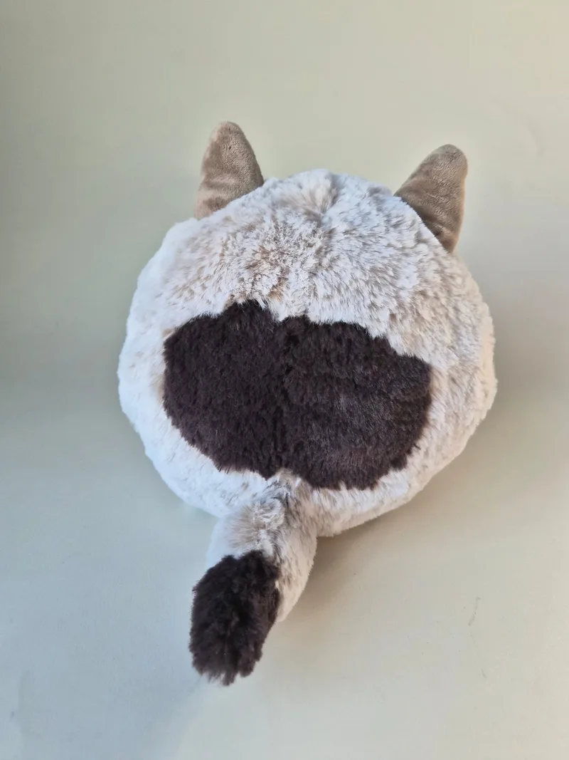 Back view of the round wolf plush showing a dark espresso back patch and a short dark-tipped curled tail