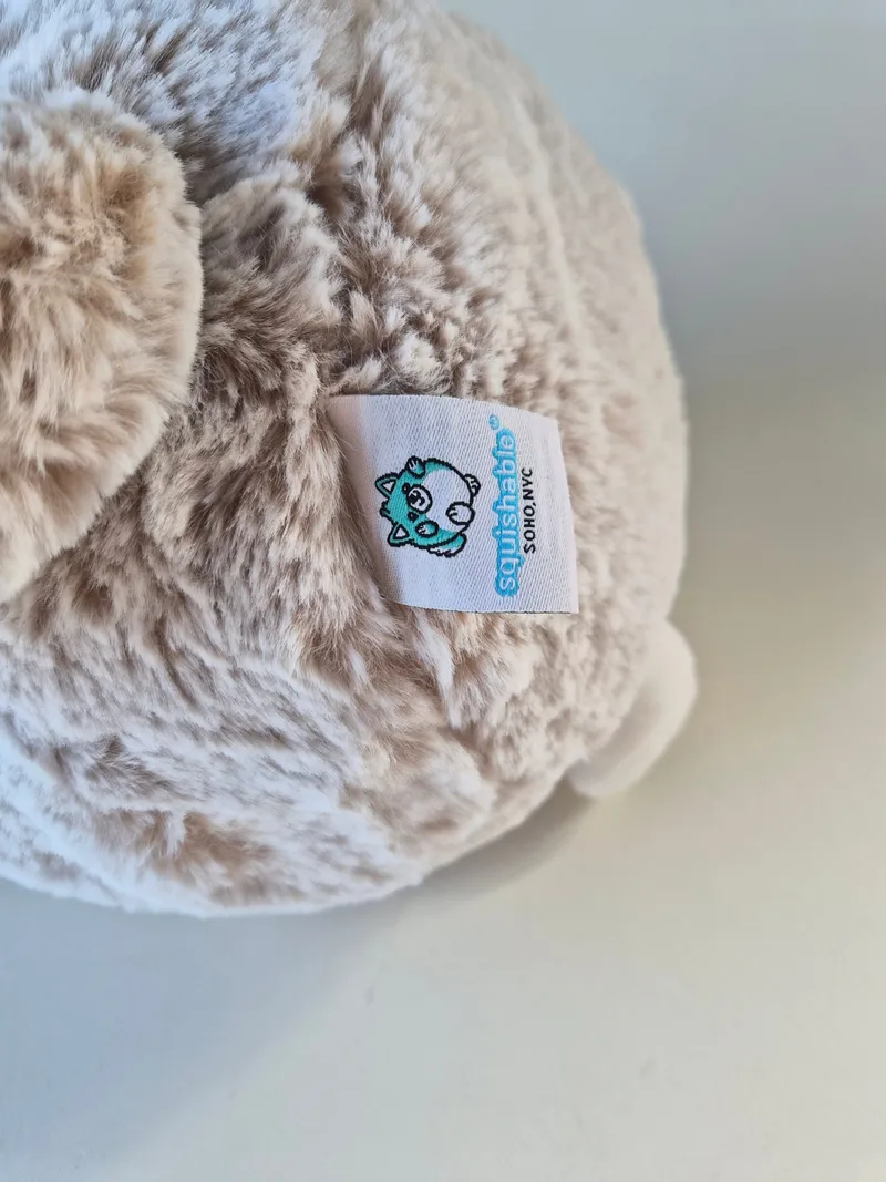 Close-up of the Squishable SoHo NYC woven tag on the wolf's cream-taupe shag