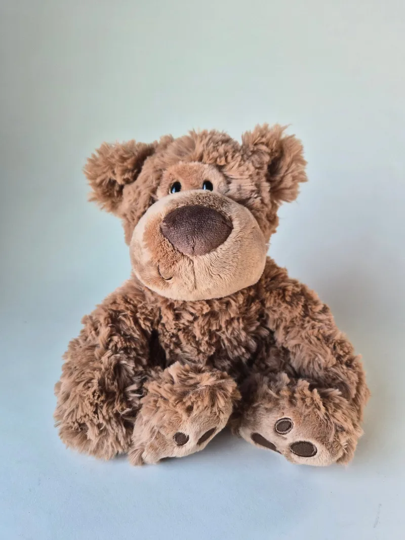 Honey-brown Gund bear sitting upright with a broad chocolate-suede nose and low dreamy eyes