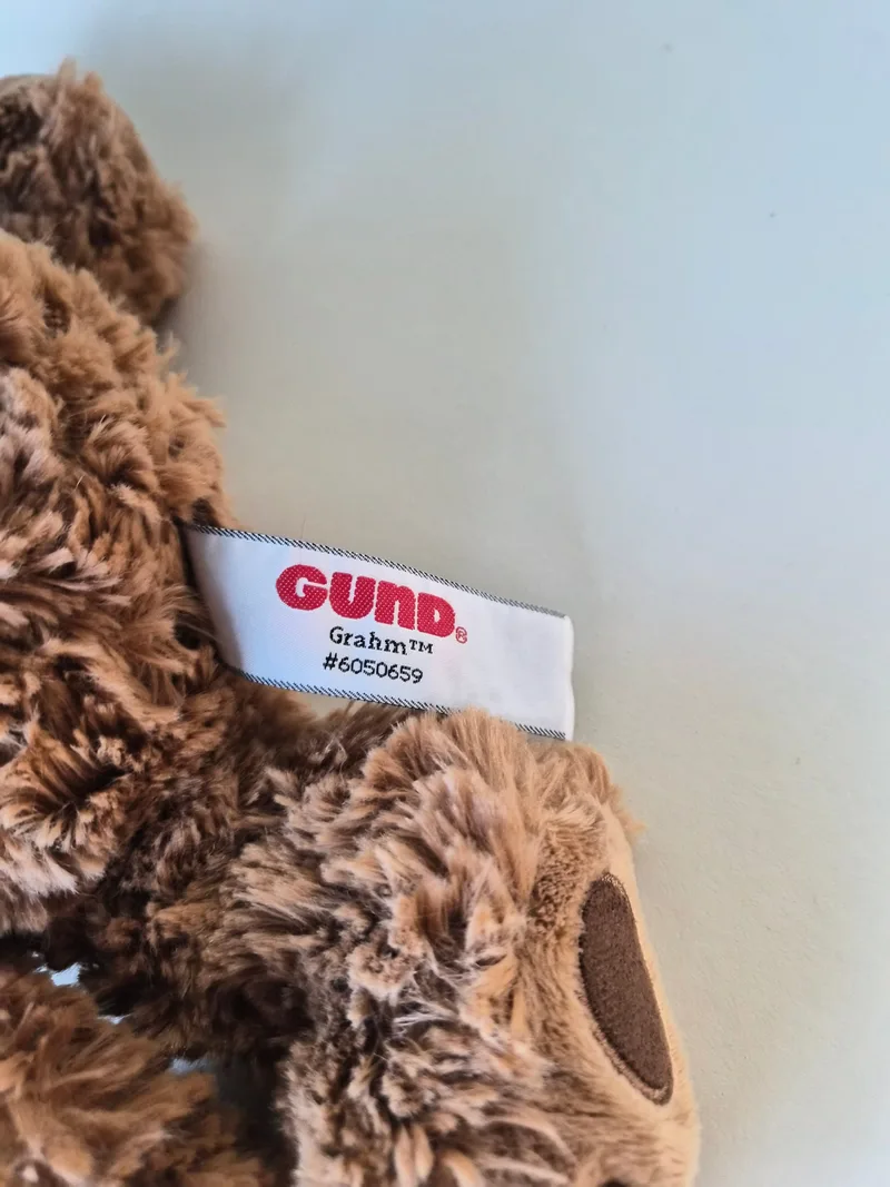 Close-up of the white GUND "Grahm" side-seam tag reading #6050659 beside a stitched foot pad