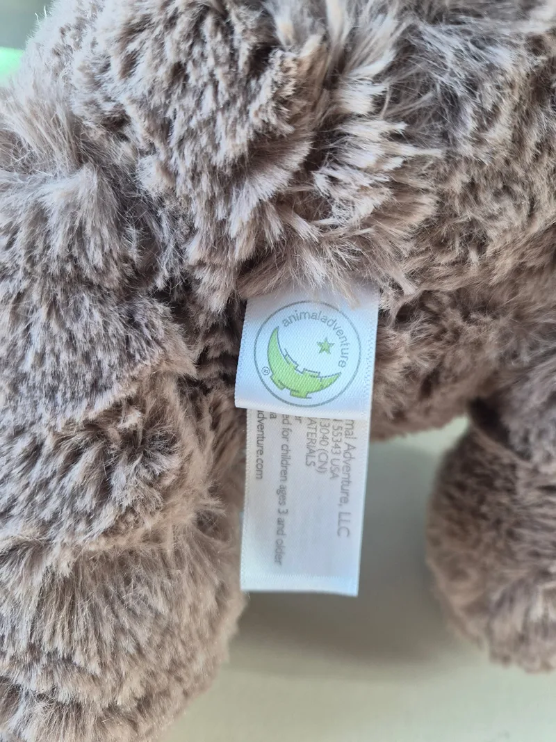Close-up of the bear's white Animal Adventure LLC seam tag among grey fur