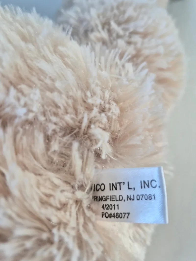 Close-up of the bear's white seam tag reading Dico Int'l, Inc., Springfield NJ, dated 4/2011