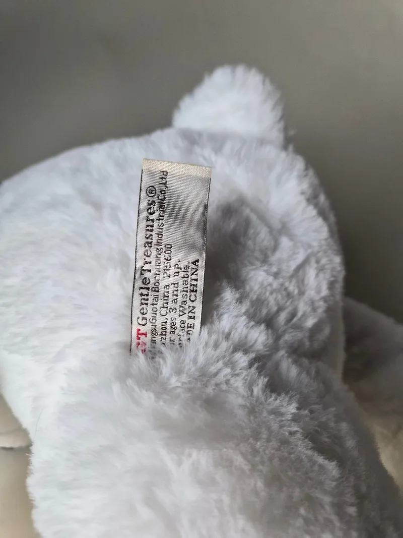 Close-up of the woven Gentle Treasures care tag reading Suzhou, China, ages 3 and up, surface washable, made in China