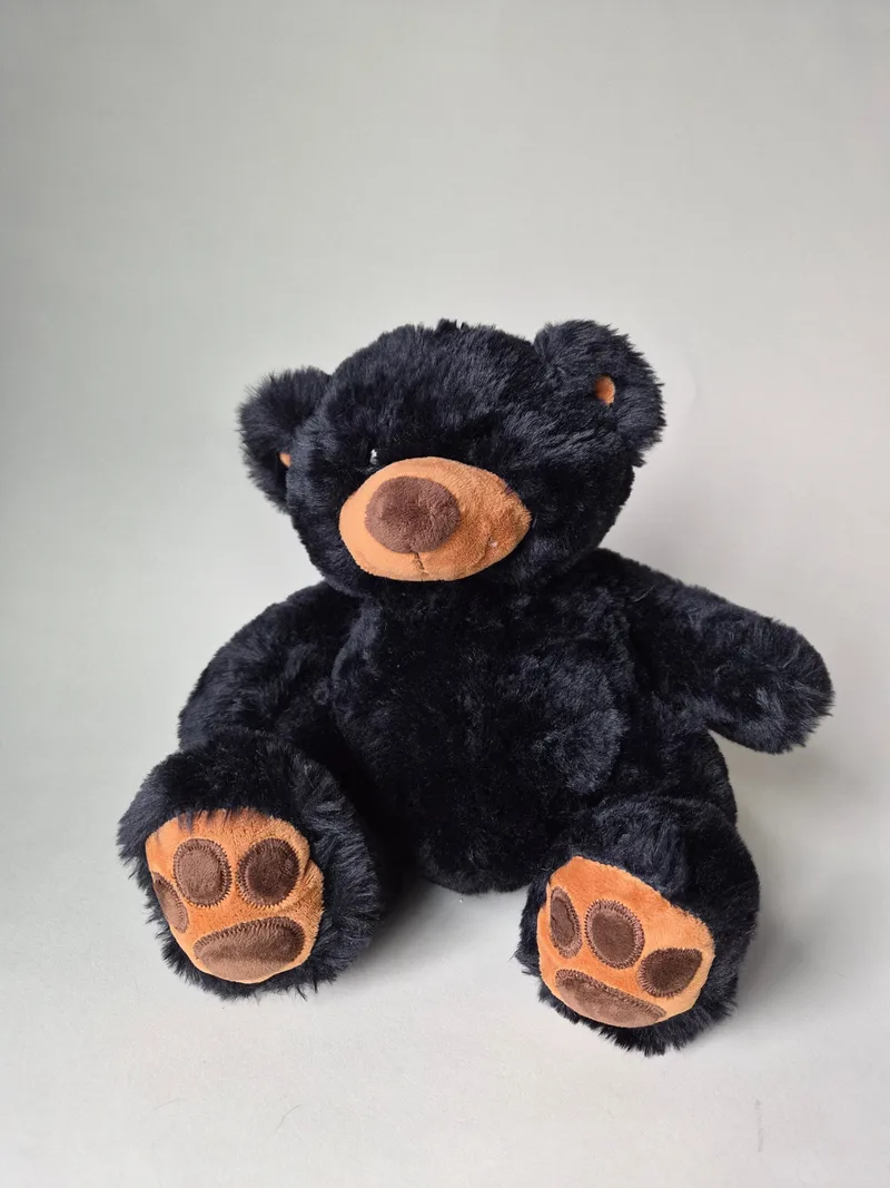 Black Wishpets teddy bear seated, with tan-and-cocoa muzzle and stitched-claw brown paw pads on both feet