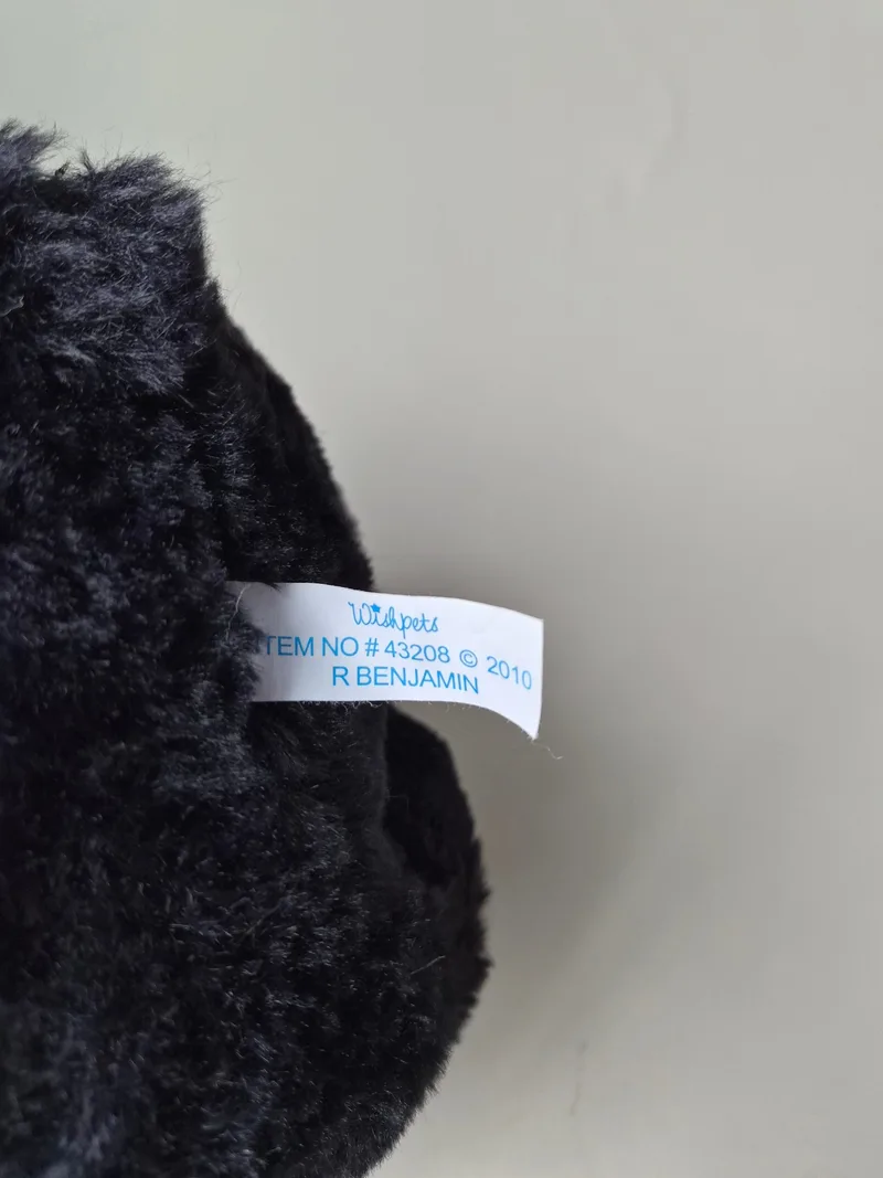 Close-up of the bear's white Wishpets tag reading item no. 43208, 2010, R Benjamin