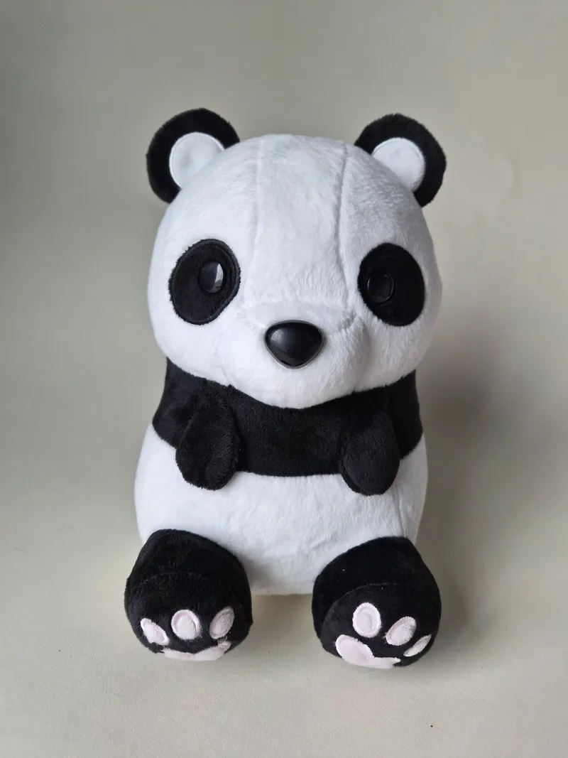 Front view of a sitting black-and-white panda plush with glossy black eyes, black nose, black chest band and pink embroidered pads on both black feet