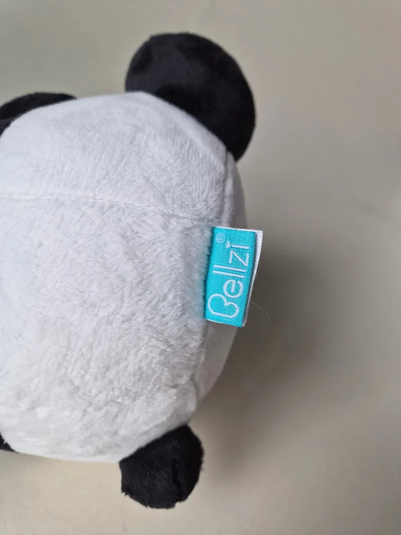 Close-up of the teal Bellzi woven tag stitched into the panda plush's side seam