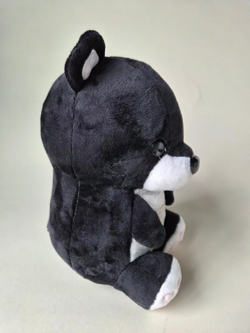 Side view of the black bear showing dense short plush, glossy black eye and grey-lined ear