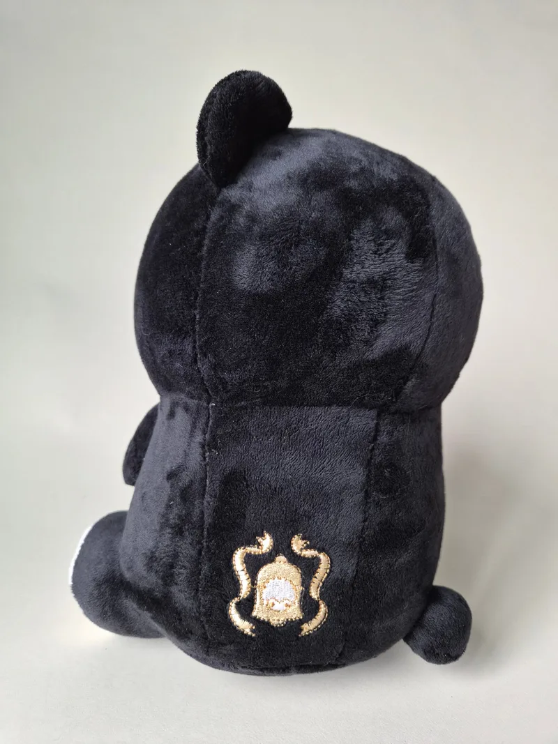 Back view of the bear showing a small gold and cream embroidered crest stitched low on the black plush