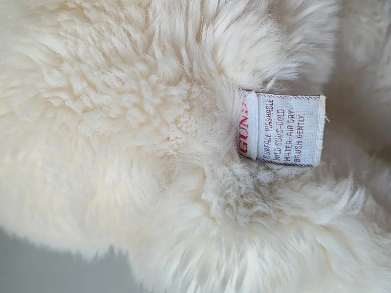 The Gund care label seen in place along the bear's rear seam among cream plush