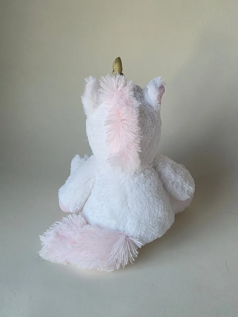 Rear view of the same white unicorn showing a pale pink faded mane and tail and the gilt horn.