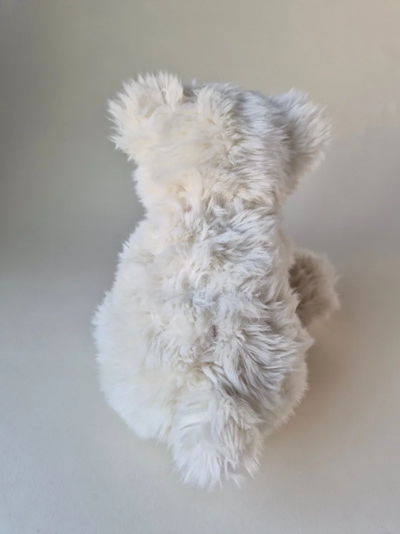 Back view of the same cream teddy bear showing swirled, softly matted fur and faint pale shadowing between the shoulders