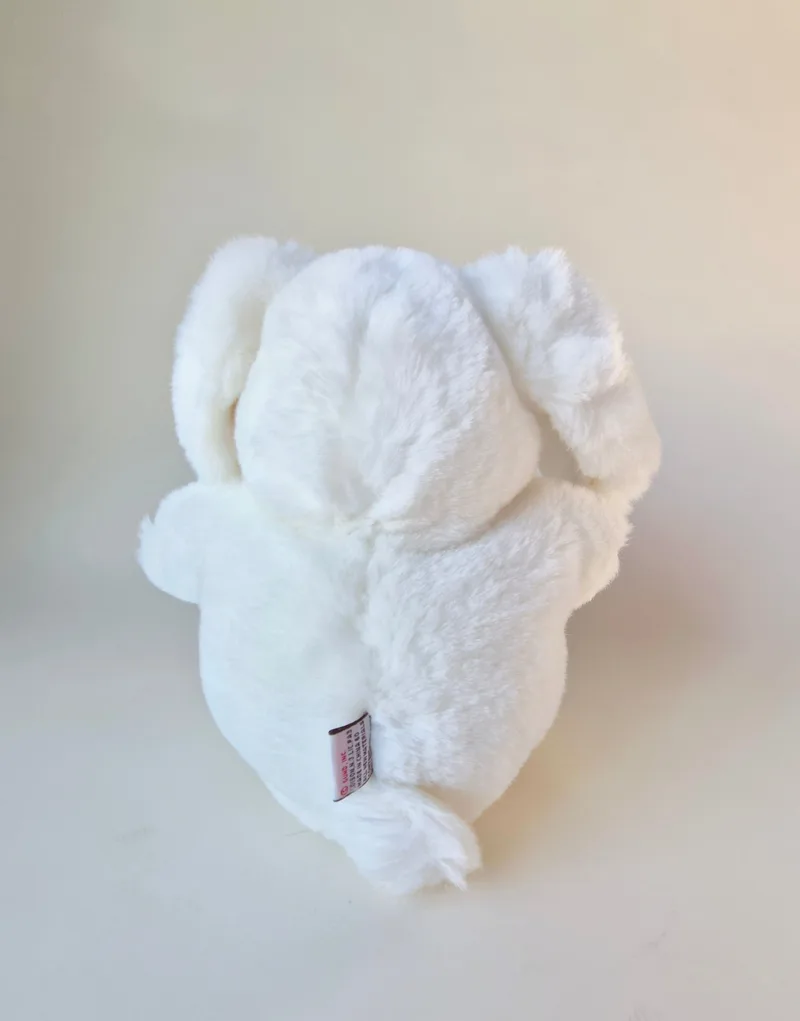 Back view of the prone bunny with tucked hind legs and a small red-script care label at the lower back
