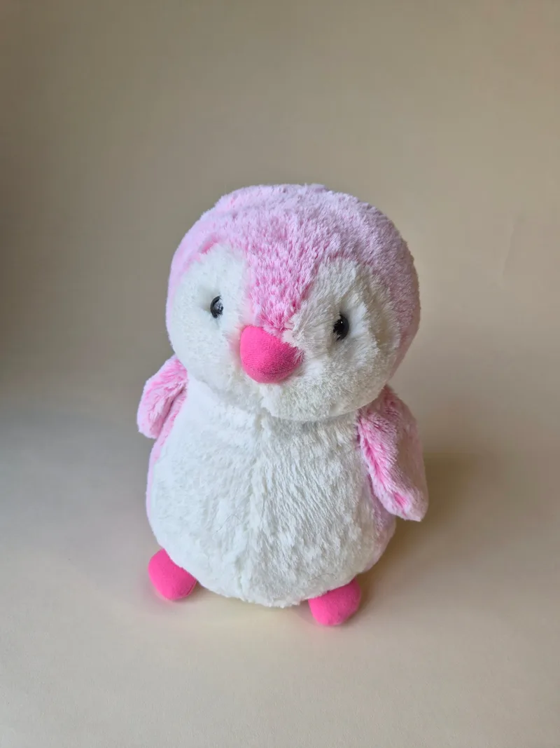 Front view of a plump pink and white penguin plush with a coral beak, black bead eyes and bright pink feet, standing upright