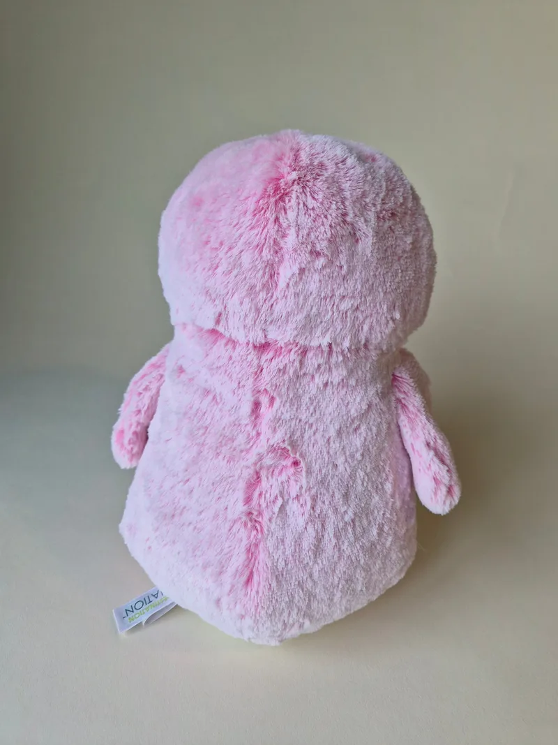 Back view of the penguin showing all-pink plush with soft whorls and a seam running down the spine, with a white tag at the lower seam