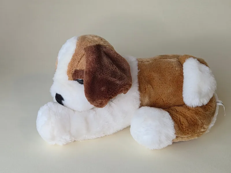 Side view of a lying-down puppy plush with honey back, chocolate ear, and white face and paws