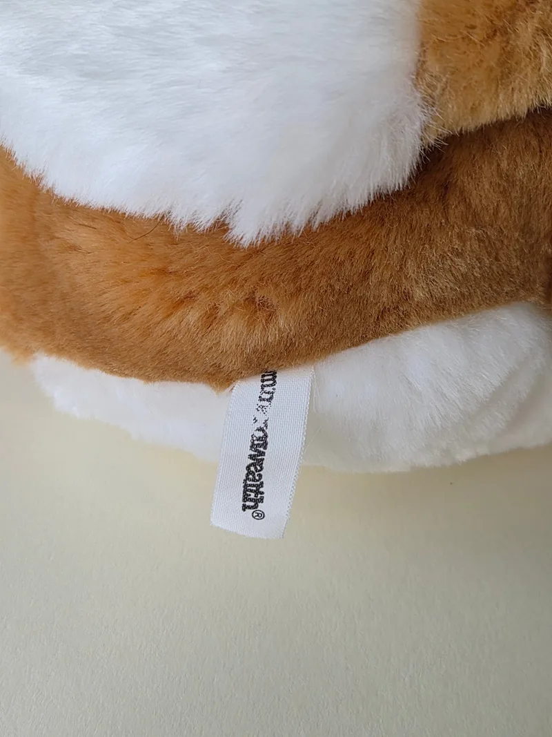 Detail of the woven hem tag on white and honey plush
