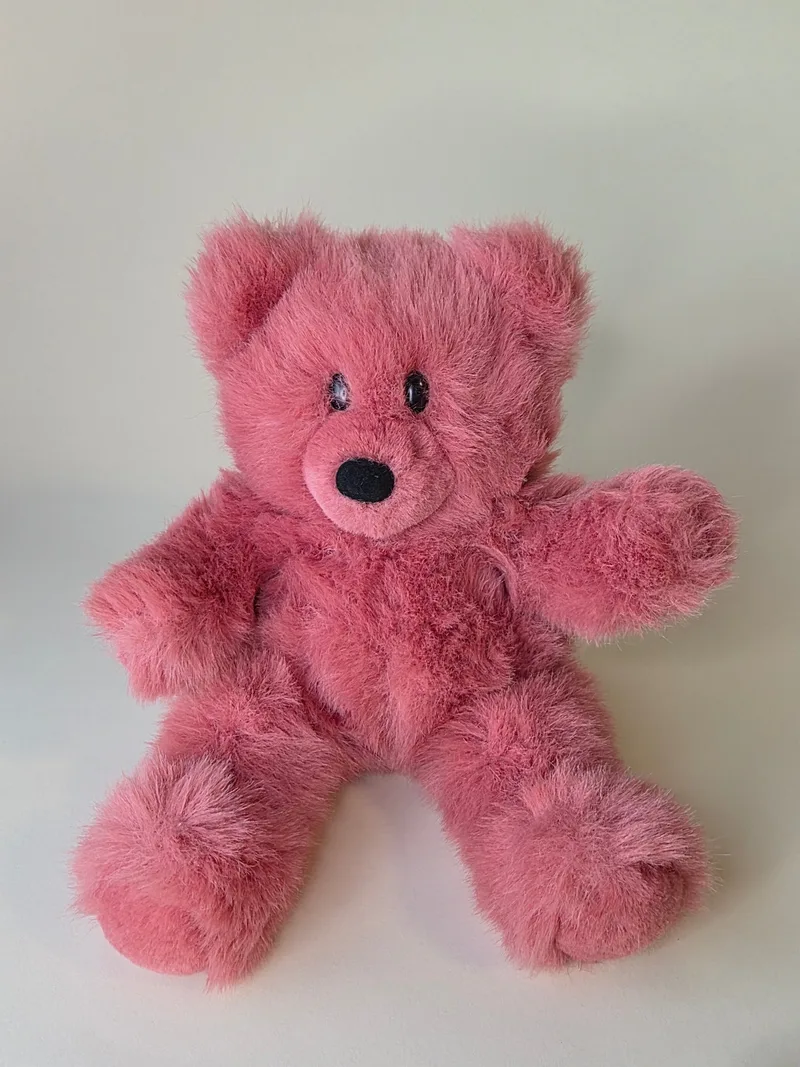 Deep raspberry-pink long-pile teddy bear seated, with glossy eyes and a black velour nose