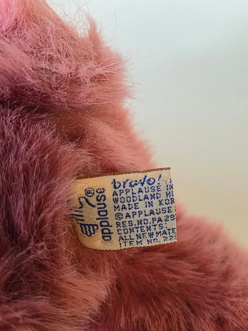 Close-up of a woven cream care tag in pink fur reading maker and shade details