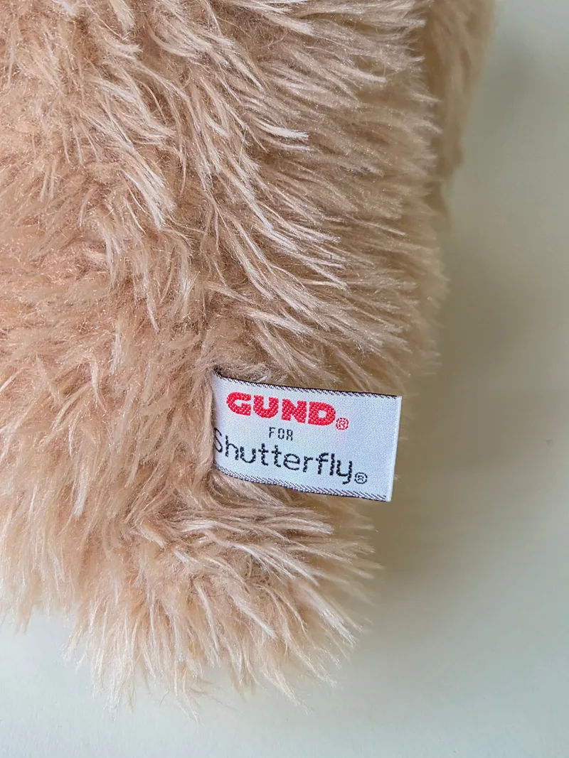 Close-up of the bear's woven tag reading Gund for Shutterfly against the blush fur