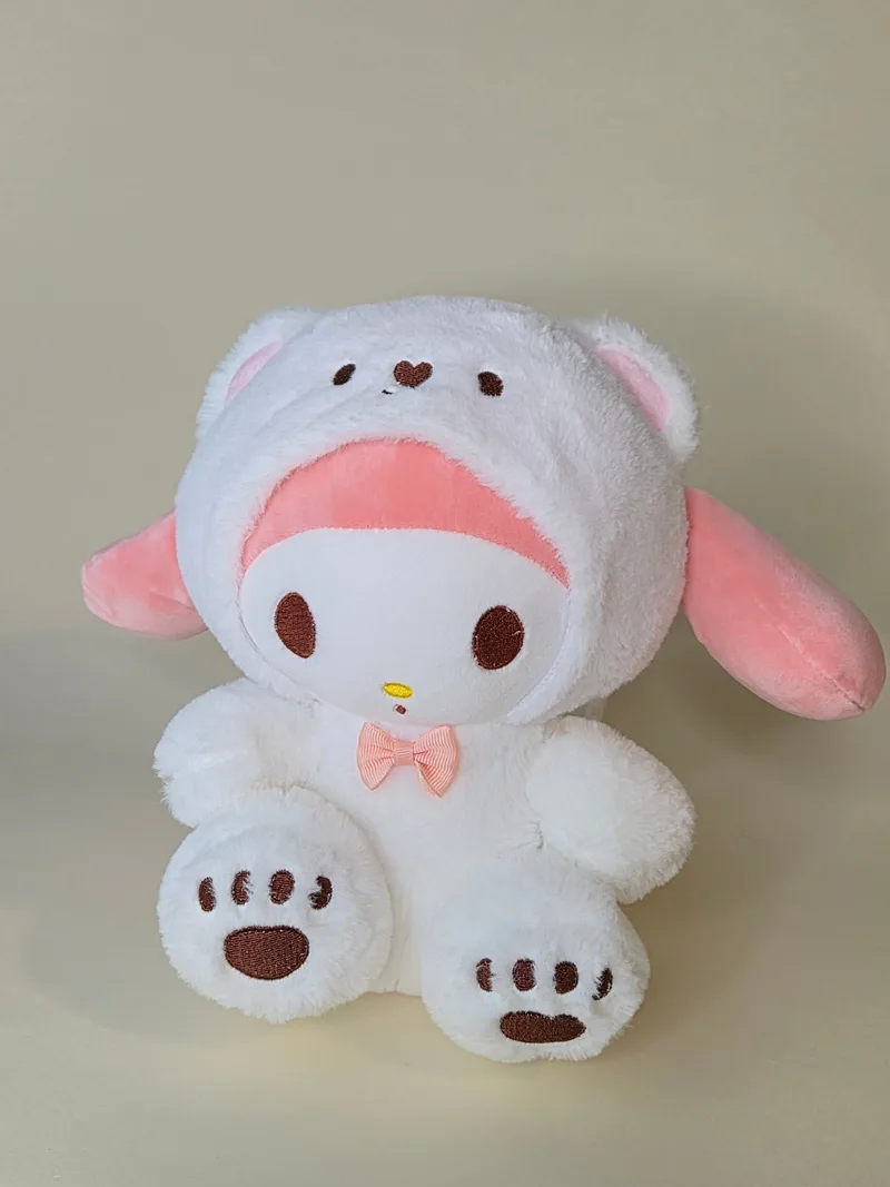 Front view of a white plush bear wearing a separate pink-lined hood, with embroidered heart and eyes, a striped bow at the throat, and paw pads showing stitched claws