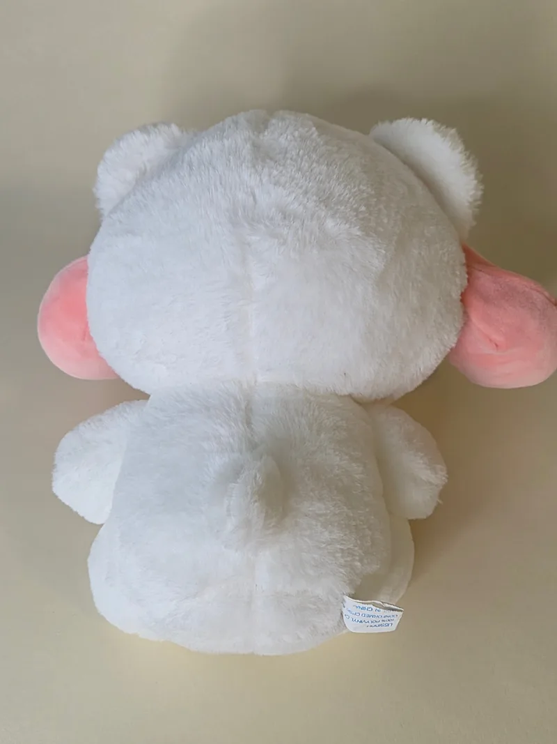 Back view of the same white bear showing the hood's pink ear backing, smooth white back fur, and a fabric tag stitched at the lower back