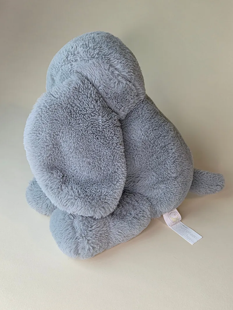 Back view of the grey plush elephant showing full ear shape and tail