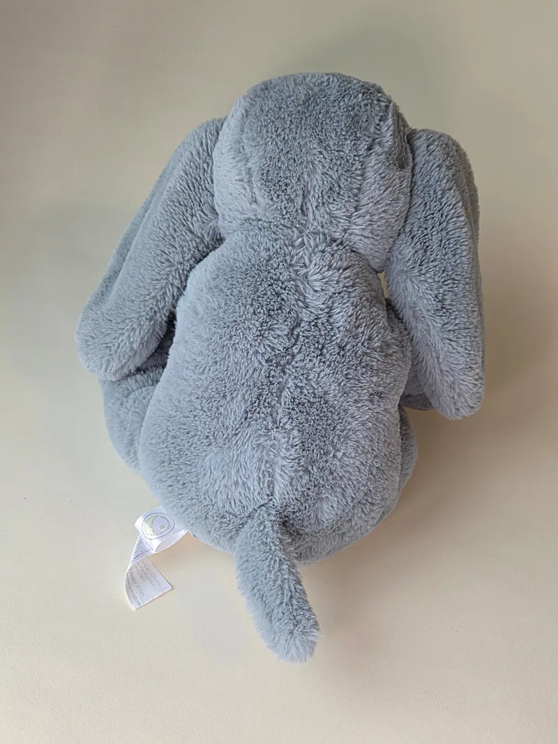 Overhead view of the plush elephant showing folded ears and fabric tag