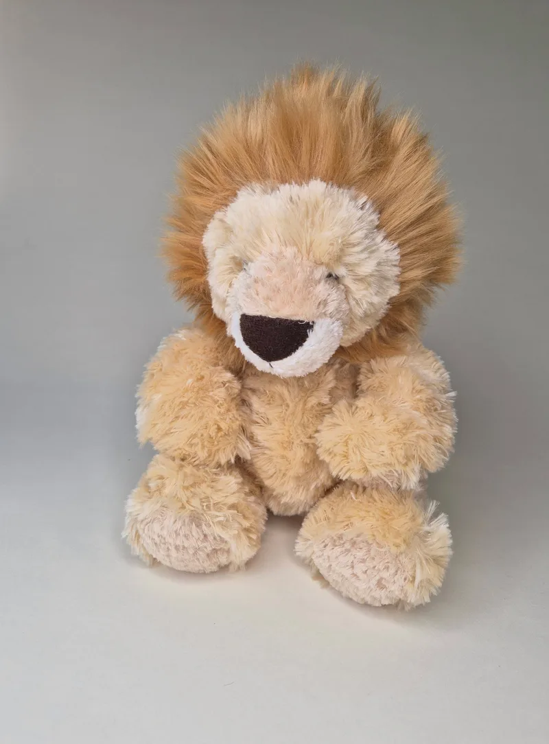 Front view of a plush lion-style bear with a large layered gold mane, cream face, and dark triangular nose, seated against a grey background.