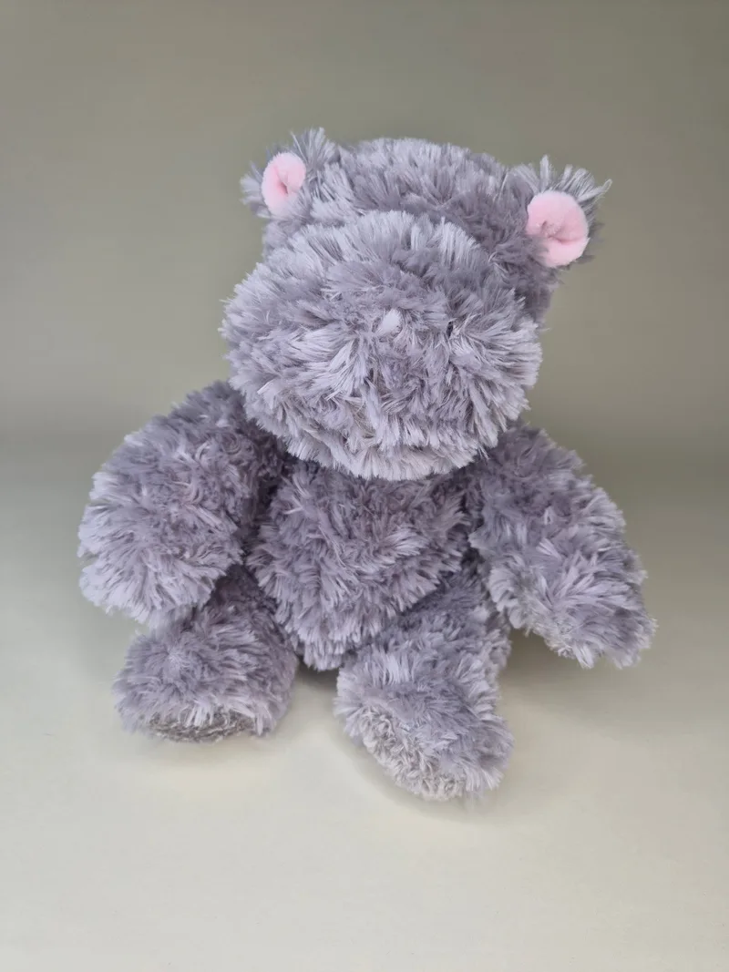 Three-quarter view of the grey plush bear sitting upright, showing full shaggy fur texture