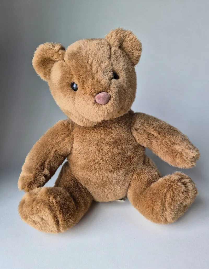 Classic honey-brown teddy bear sitting upright and facing forward, with black eyes and a pink velvet nose.