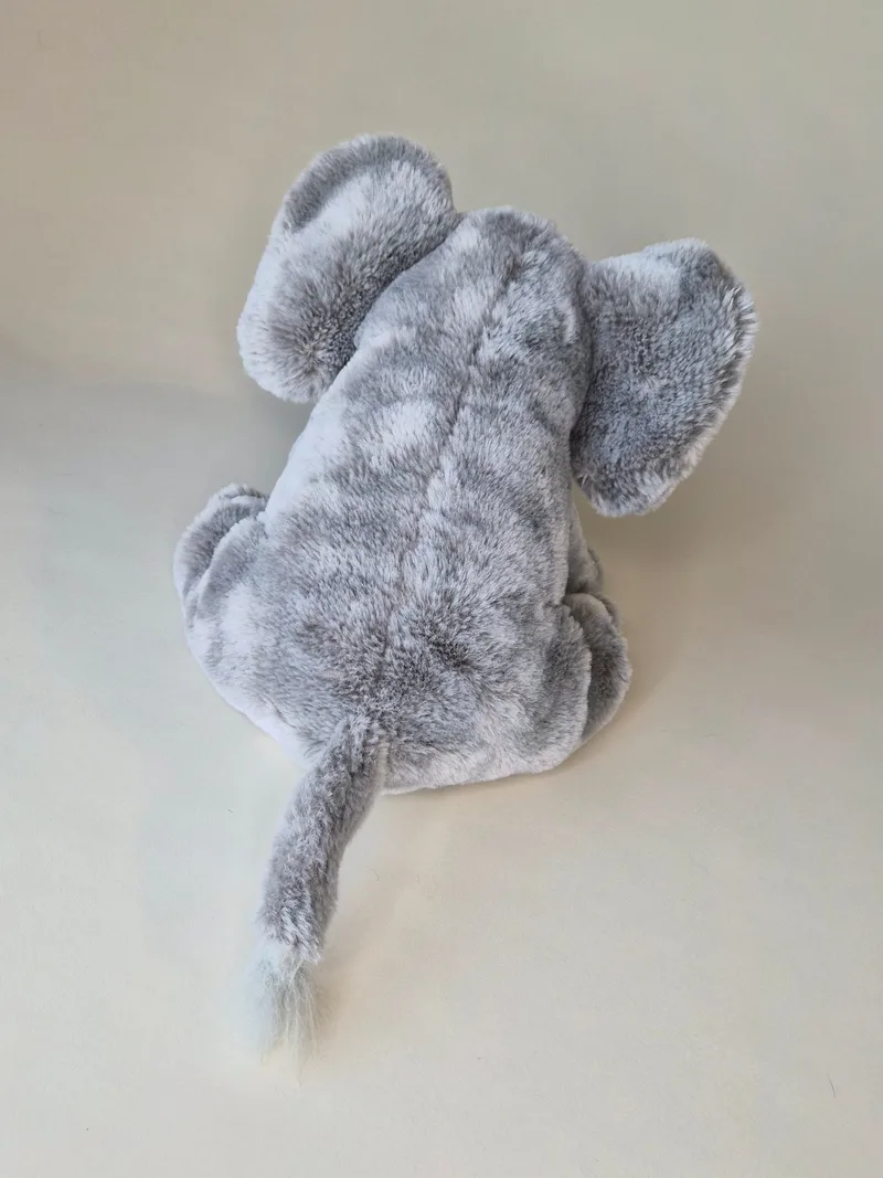 Back view of grey plush elephant showing shaded fur pattern, rounded ears, and short tail