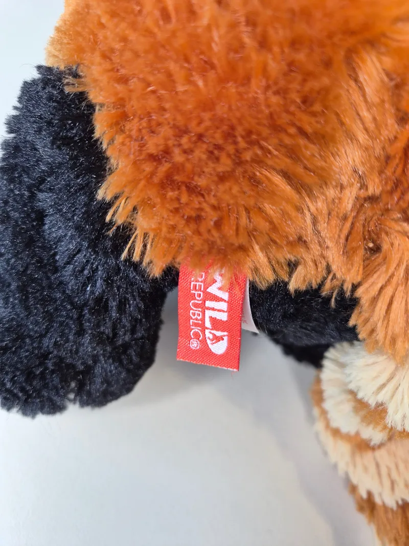 Close-up of the red Wild Republic fabric tag sewn into the fur at the plush's hip seam