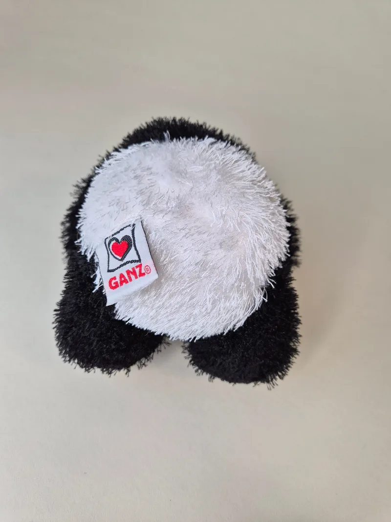 Back of the panda bear showing the GANZ heart tag and a small rainbow-striped fabric label stitched to one foot.
